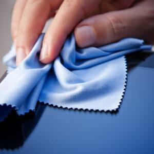 Hand cleaning a tablet PC with a cloth. Shallow depth of field.