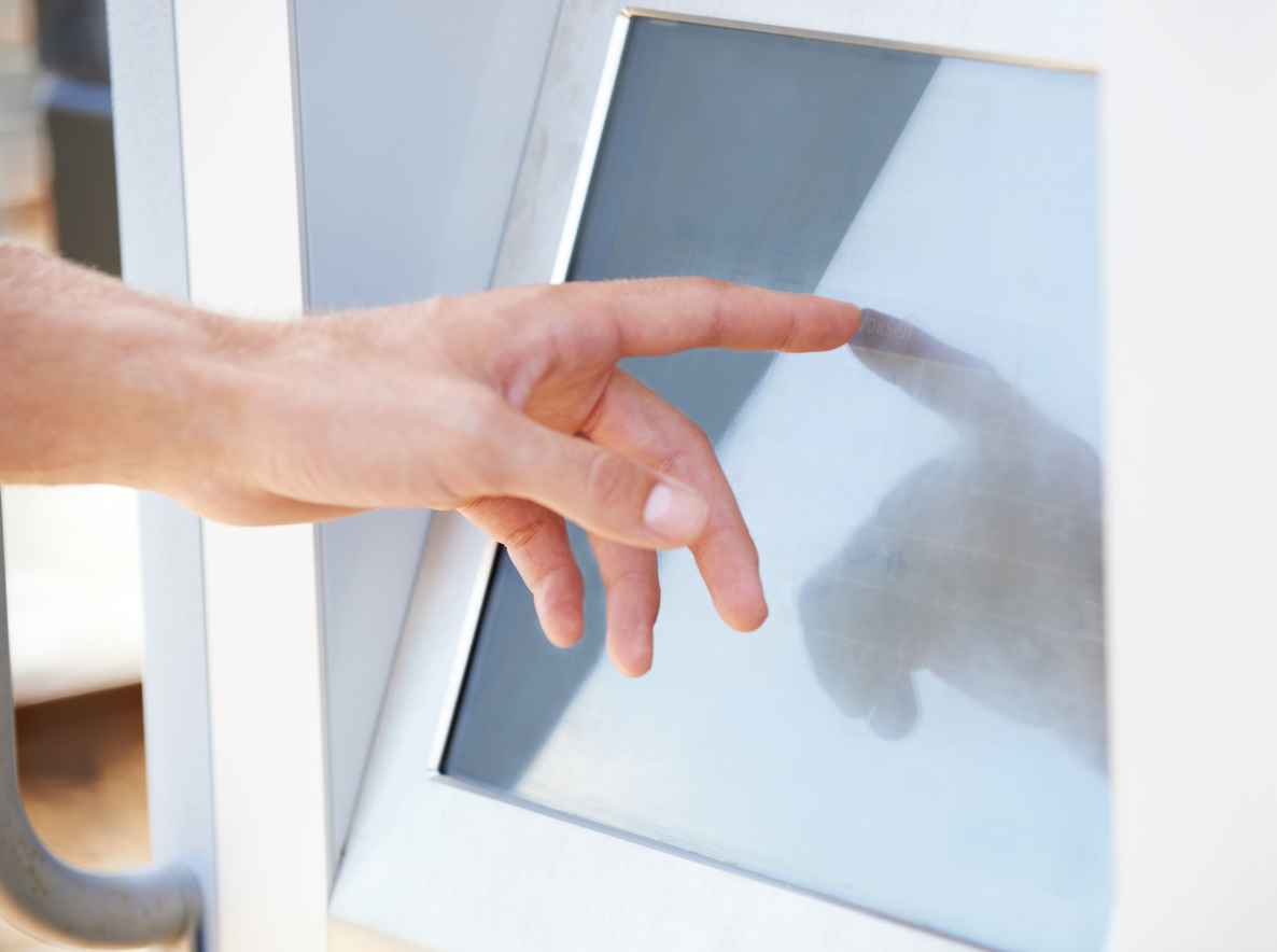 Cropped view of a male hand using a touchscreen ATM; The Benefits of Cover Glasses for TFT Displays and Touch Screens