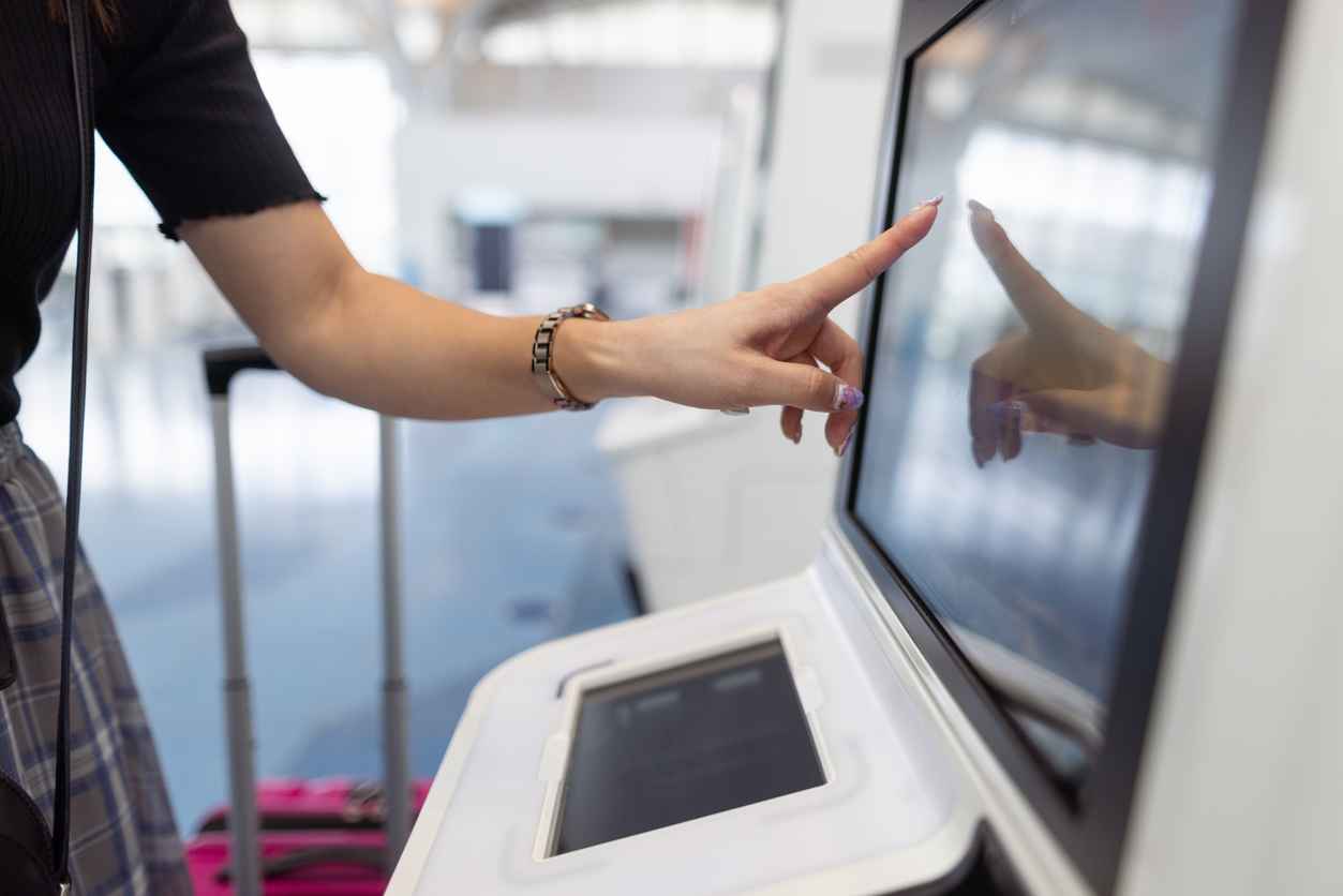 Woman using self check-in touchscreen in airport