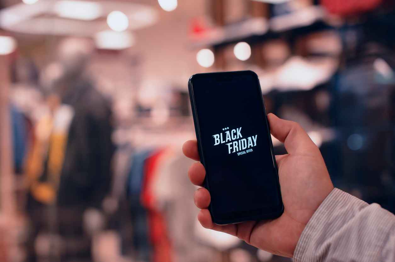 Online shopping on Black Friday. A man holds a smartphone in his hands against the background of a fashionable clothing boutique