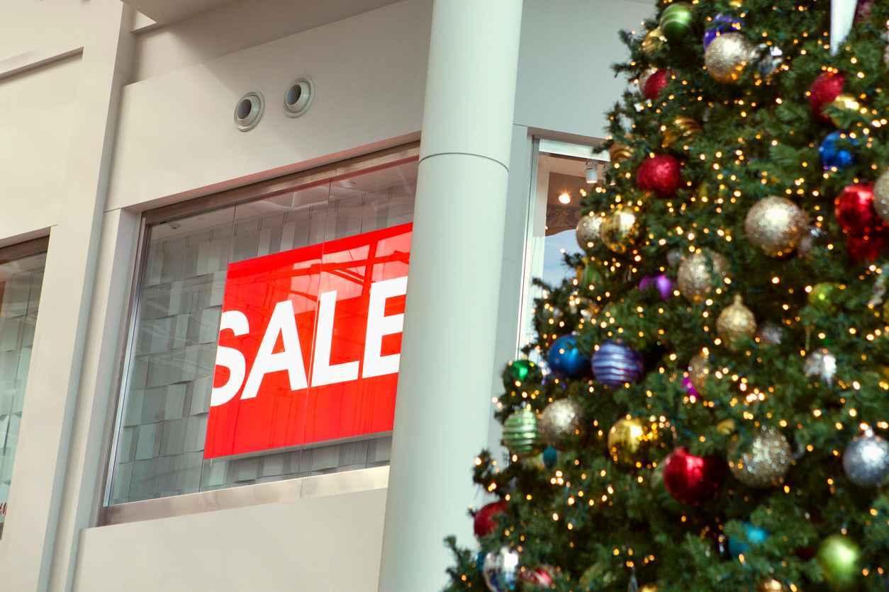 Christmas decorations hanging in front of a partially hidden "Sale" sign during the most lucrative season of the year for retail sales.