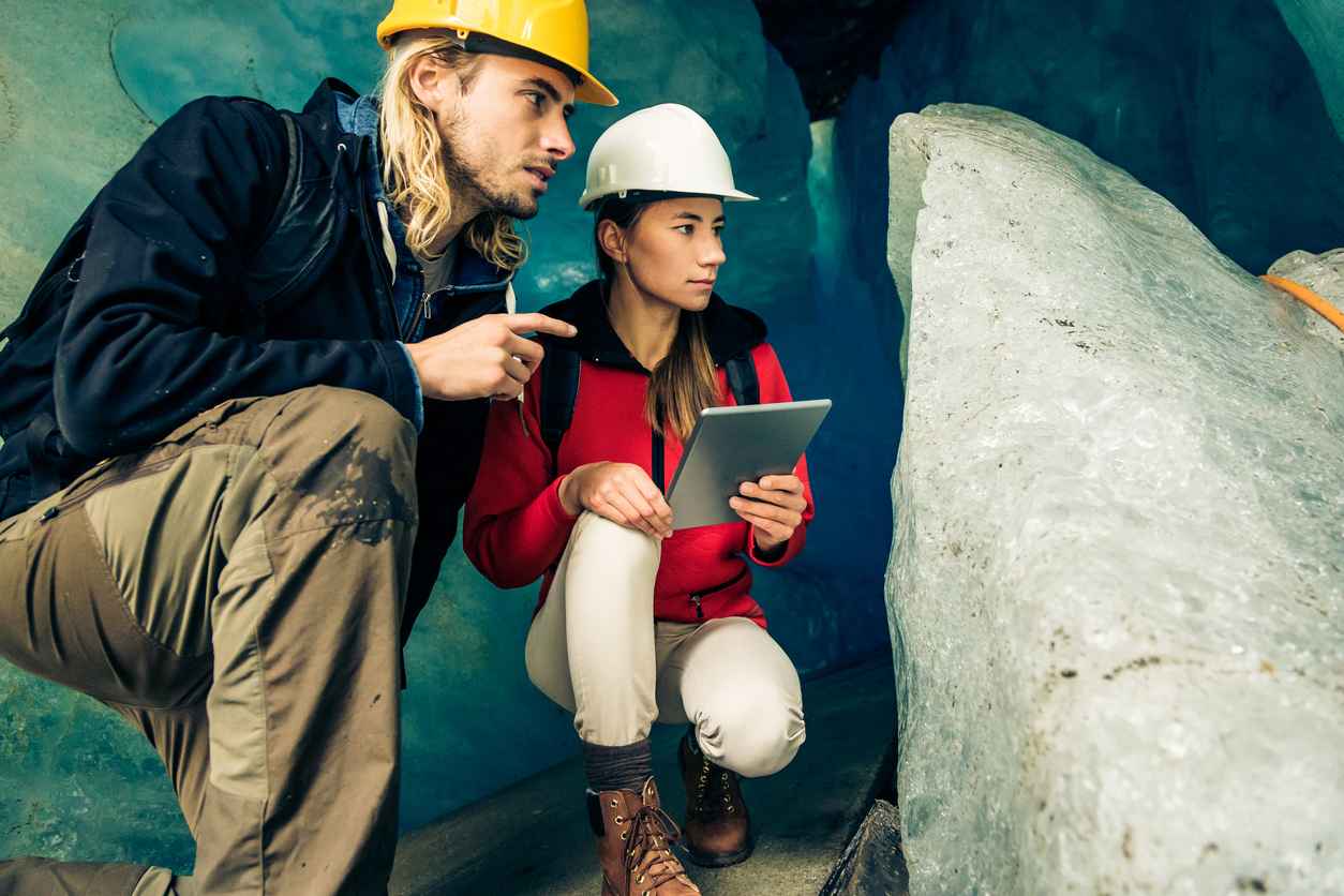 Team of Scientists Examining a Glacier Holding Touch Screens