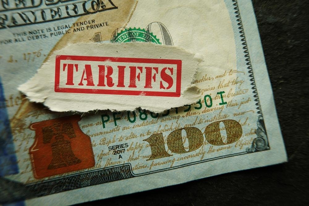"Tarrifs" stamped on a piece of paper covering a 100 dollar bill