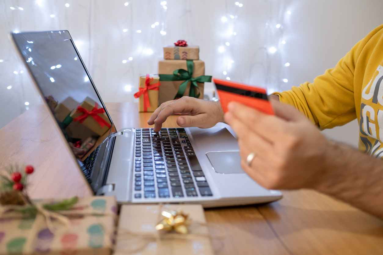 Hand of young man doing shopping online with credit card on laptop for Christmas.